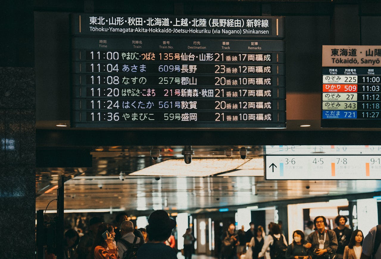 An illuminated train station departure board displaying routes in Asian characters